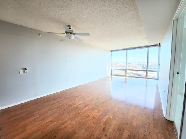 unfurnished room featuring ceiling fan, floor to ceiling windows, wood-type flooring, and a textured ceiling