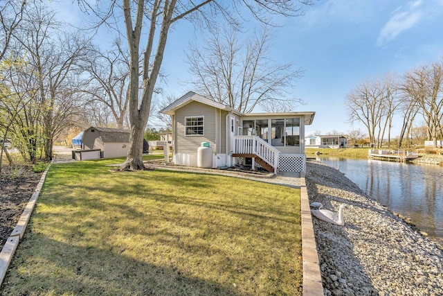 view of front of property featuring a front lawn, a sunroom, and a water view