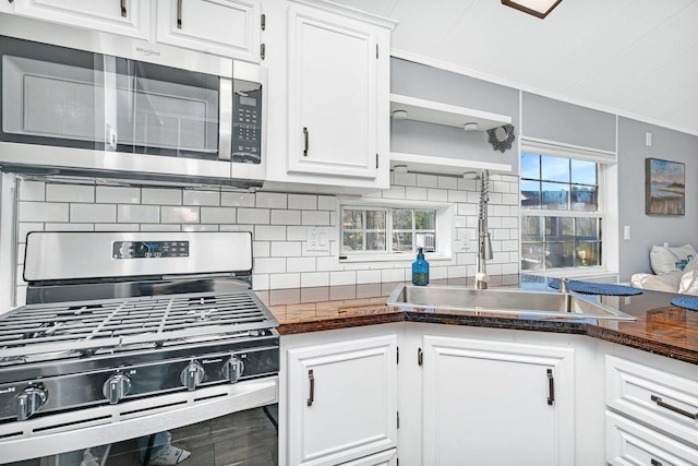 kitchen with white cabinets, ornamental molding, and stainless steel appliances