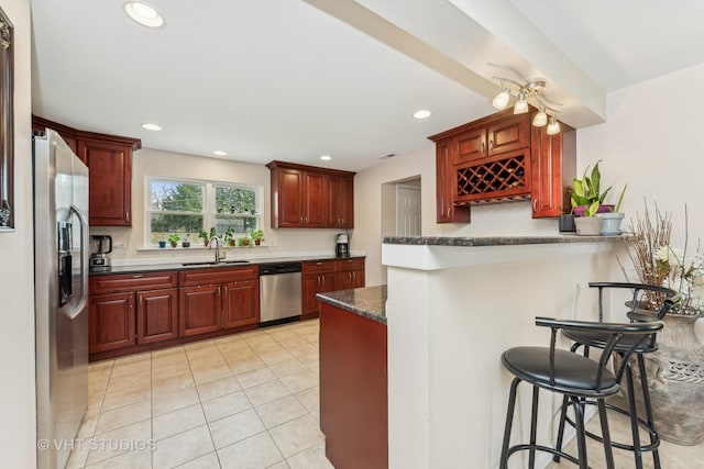 kitchen featuring kitchen peninsula, appliances with stainless steel finishes, sink, dark stone countertops, and a breakfast bar area