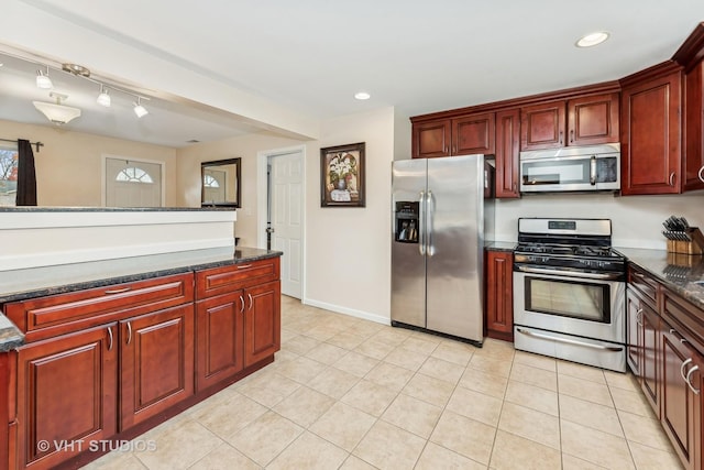 kitchen featuring dark stone counters, light tile patterned floors, and stainless steel appliances