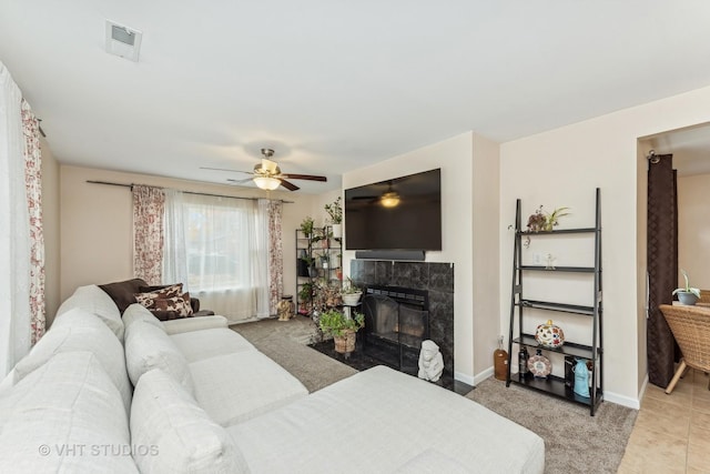 living room with ceiling fan, light tile patterned floors, and a tile fireplace