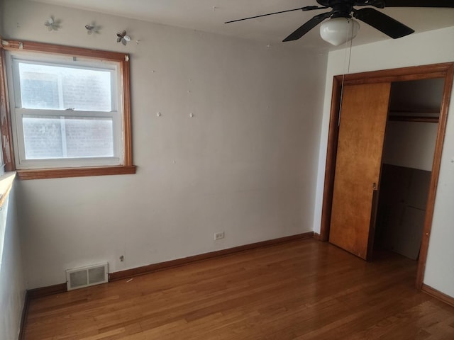 unfurnished bedroom with ceiling fan, a closet, and hardwood / wood-style flooring