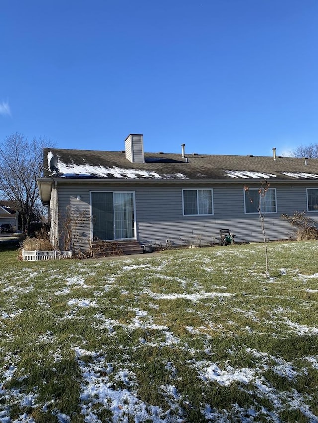 snow covered rear of property with a lawn