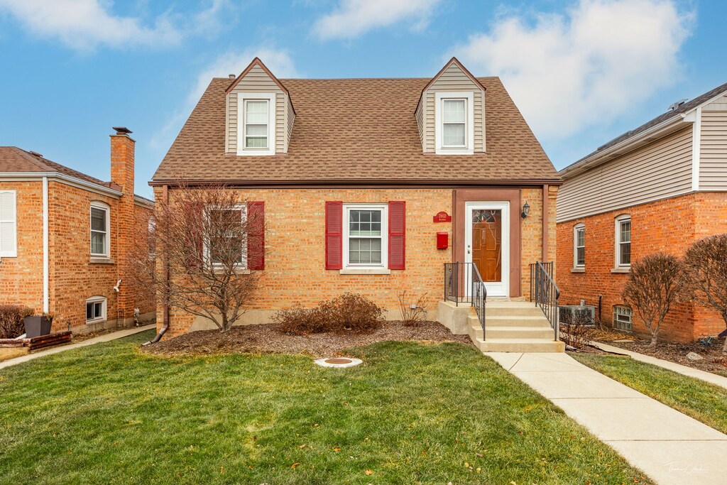 7802 W Ardmore Ave, Chicago, IL 60631 - new england style home featuring brick siding, a front yard, a shingled roof, and central air condition unit