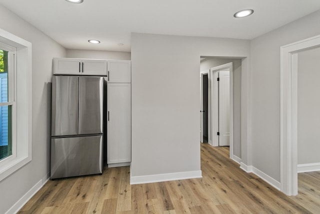 kitchen with stainless steel refrigerator, light hardwood / wood-style flooring, and white cabinets