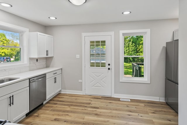 kitchen with backsplash, light wood-type flooring, white cabinetry, and stainless steel appliances