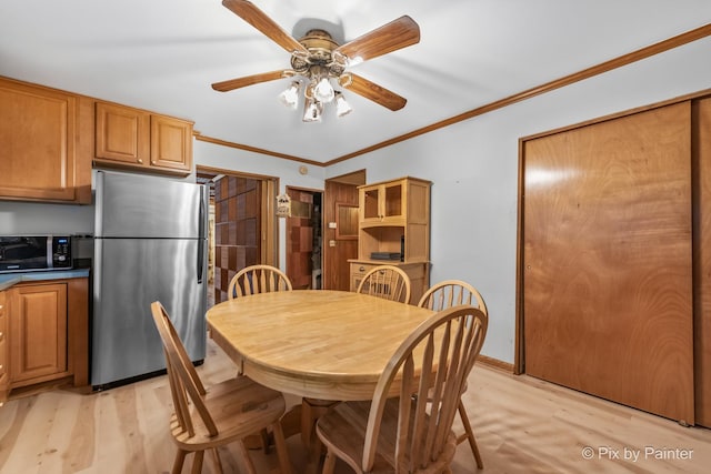 dining space with ceiling fan, ornamental molding, and light wood-type flooring