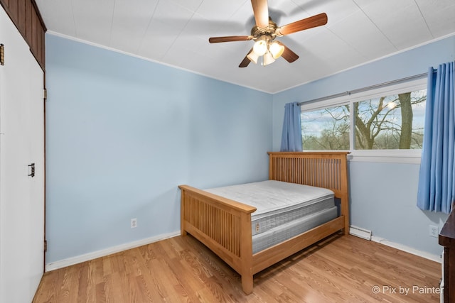 bedroom with baseboard heating, ceiling fan, and light hardwood / wood-style flooring