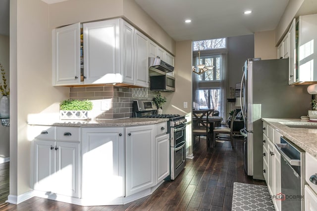 kitchen with white cabinetry, tasteful backsplash, light stone countertops, and appliances with stainless steel finishes