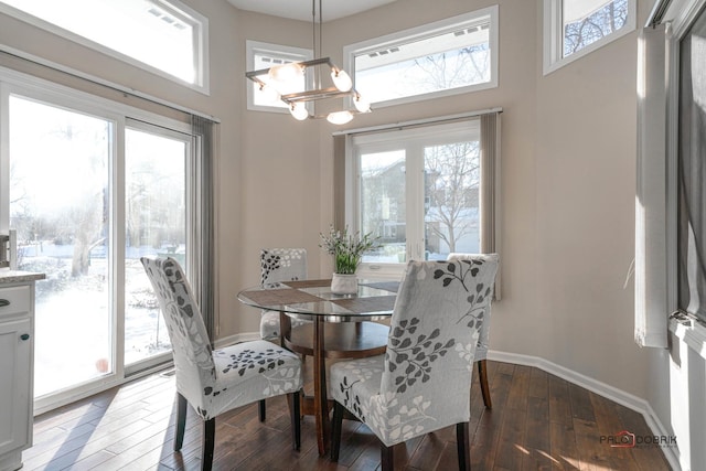 dining room with dark wood-type flooring, a chandelier, and a towering ceiling