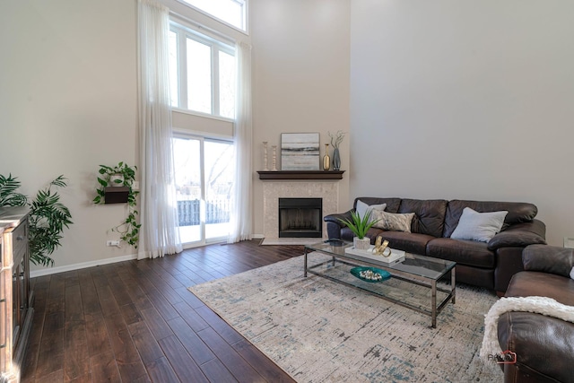 living room with a tiled fireplace, dark hardwood / wood-style floors, and a high ceiling