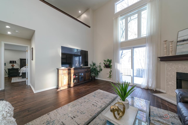 living room with a towering ceiling, a fireplace, and dark hardwood / wood-style flooring