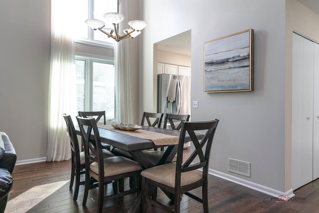 dining area featuring a high ceiling, dark hardwood / wood-style floors, and a chandelier