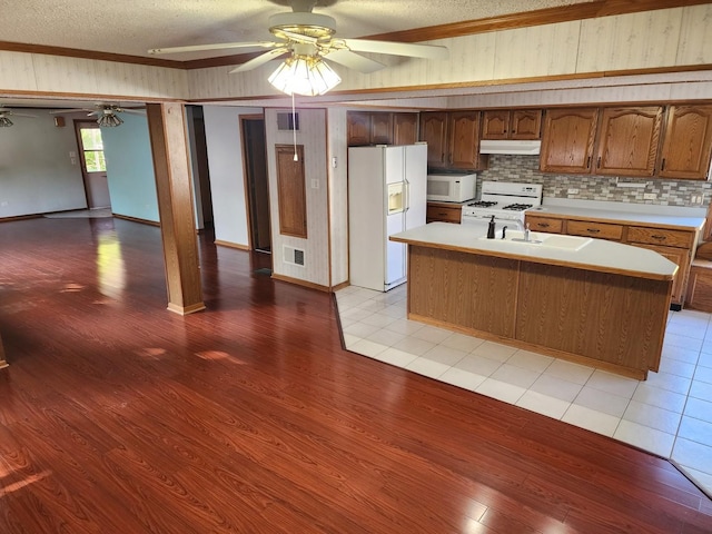 kitchen featuring a textured ceiling, a kitchen island with sink, sink, and white appliances