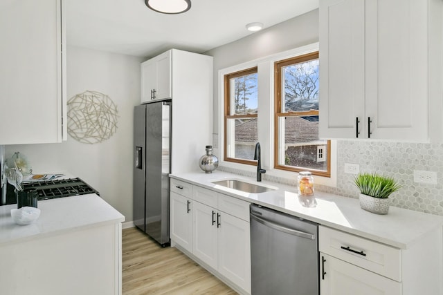 kitchen with light hardwood / wood-style floors, sink, white cabinetry, and stainless steel appliances