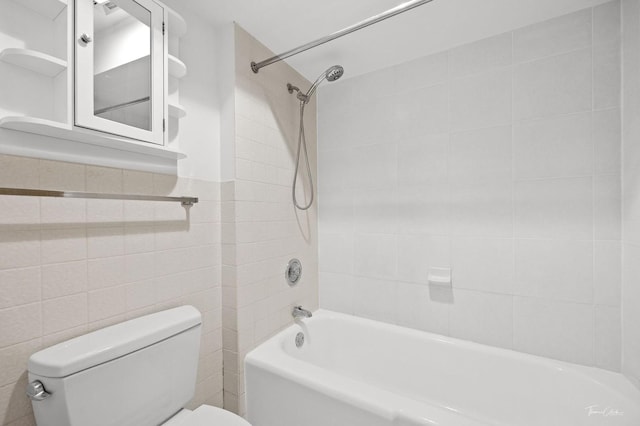 bathroom featuring tile walls, tiled shower / bath, and toilet