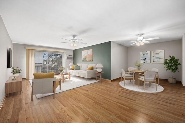 living room featuring light wood-type flooring, ceiling fan, and a wall mounted air conditioner