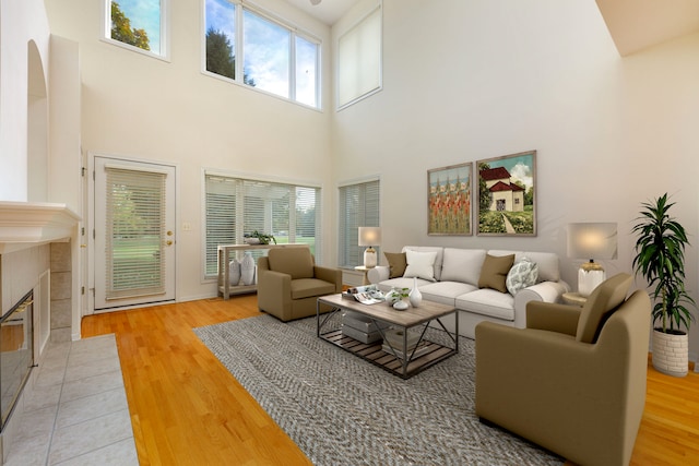 living room featuring a towering ceiling, hardwood / wood-style flooring, and a tiled fireplace