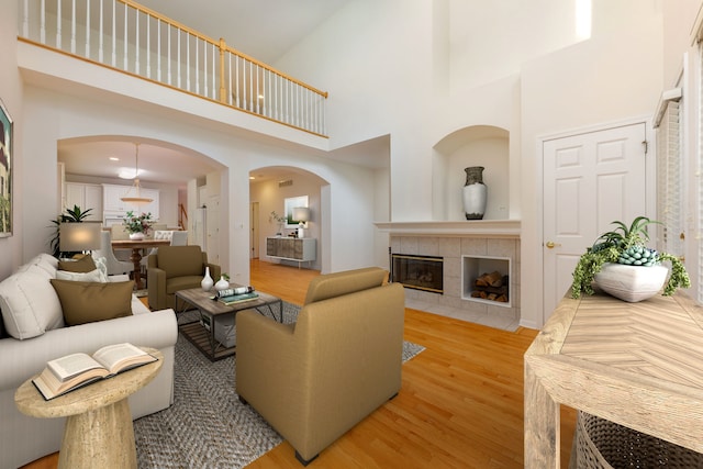 living room featuring a high ceiling, light hardwood / wood-style floors, and a tiled fireplace