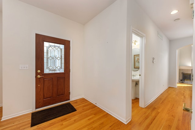 entryway with a tiled fireplace and light hardwood / wood-style flooring