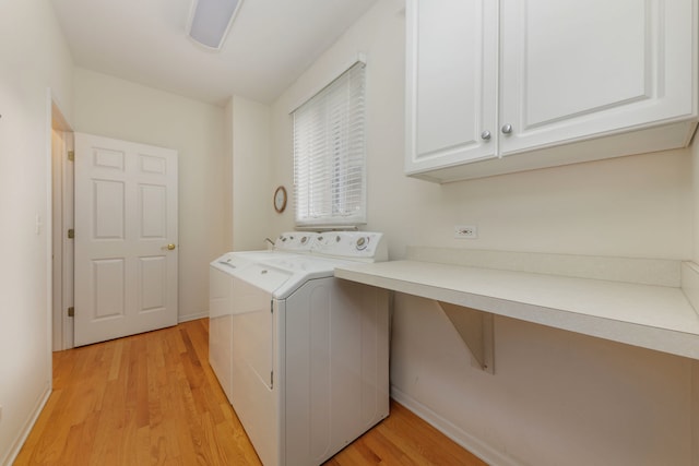 laundry area featuring cabinets, washing machine and dryer, and light hardwood / wood-style floors