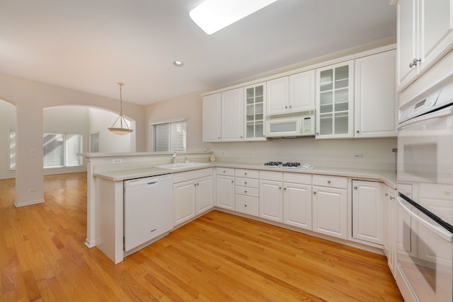 kitchen featuring pendant lighting, white cabinets, white appliances, and light hardwood / wood-style flooring