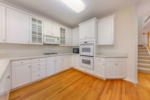 kitchen with white cabinets, white appliances, and light wood-type flooring