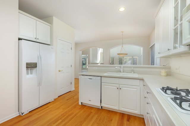 kitchen with sink, hanging light fixtures, white appliances, white cabinets, and light wood-type flooring