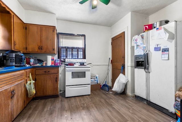 kitchen featuring a textured ceiling, ceiling fan, dark hardwood / wood-style floors, and white appliances