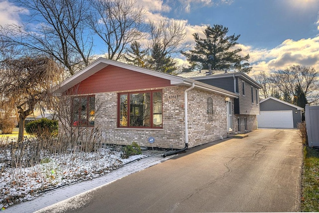 view of snowy exterior featuring a garage and an outbuilding