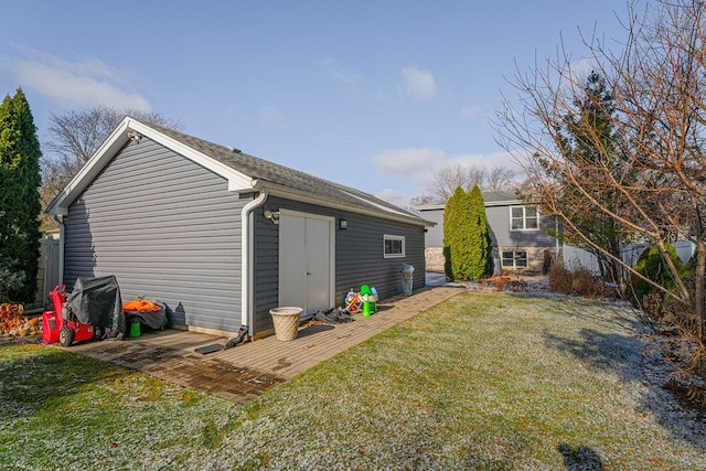 rear view of property featuring a yard and an outbuilding