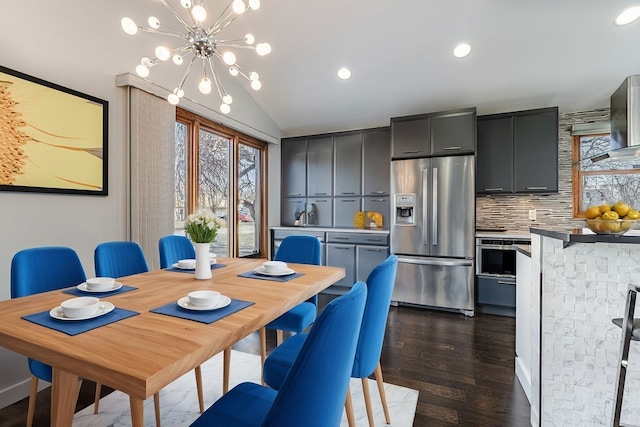 dining area with dark hardwood / wood-style flooring, a chandelier, and lofted ceiling