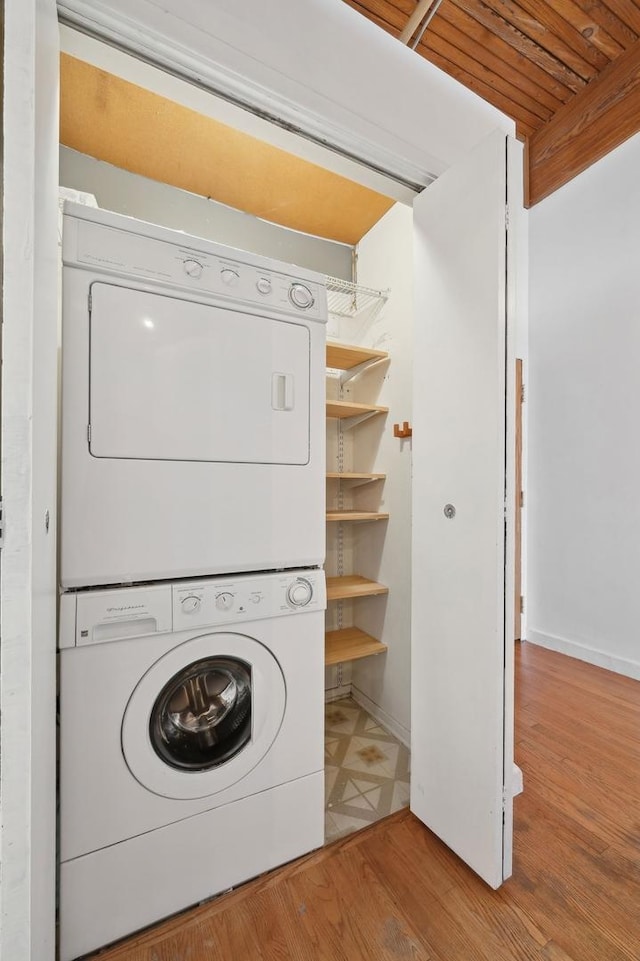 laundry area with wood-type flooring and stacked washer / drying machine