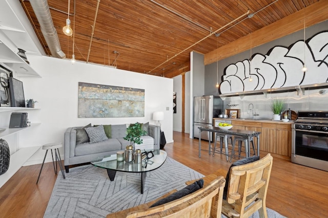 living room with light hardwood / wood-style floors, wooden ceiling, and sink