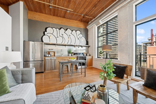 living room with light wood-type flooring, a wealth of natural light, and wooden ceiling