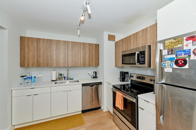 kitchen featuring backsplash, white cabinets, sink, light hardwood / wood-style floors, and stainless steel appliances