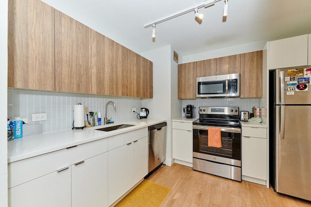 kitchen featuring white cabinets, sink, light hardwood / wood-style flooring, decorative backsplash, and stainless steel appliances