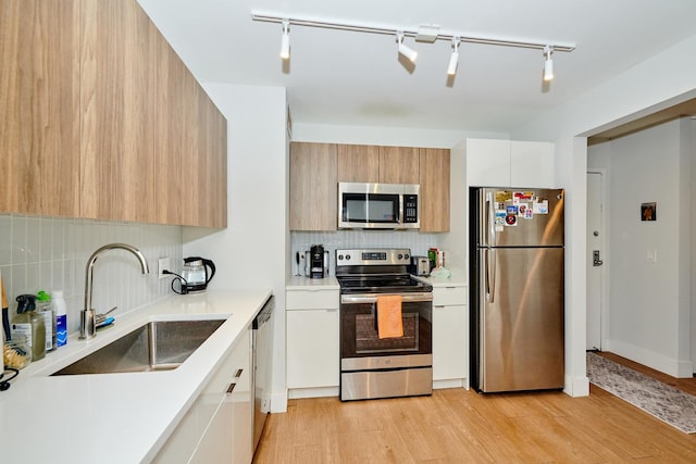 kitchen with tasteful backsplash, stainless steel appliances, sink, light hardwood / wood-style flooring, and white cabinetry