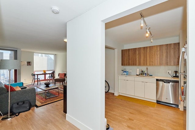 kitchen with dishwasher, light wood-type flooring, decorative backsplash, and sink