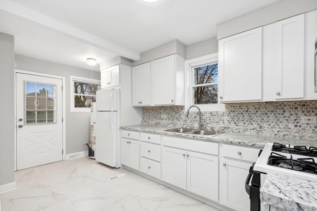 kitchen with backsplash, sink, gas range, white fridge, and white cabinetry