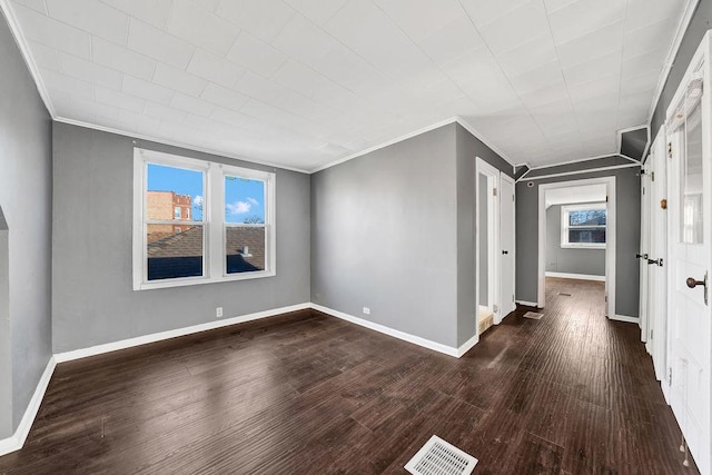 empty room with dark hardwood / wood-style floors, plenty of natural light, and crown molding