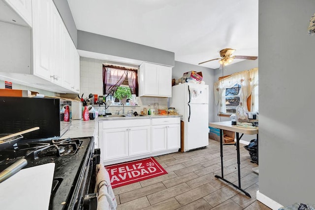 kitchen with white refrigerator, white cabinetry, and black gas range oven