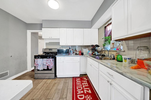 kitchen featuring backsplash, white cabinets, sink, light stone countertops, and appliances with stainless steel finishes