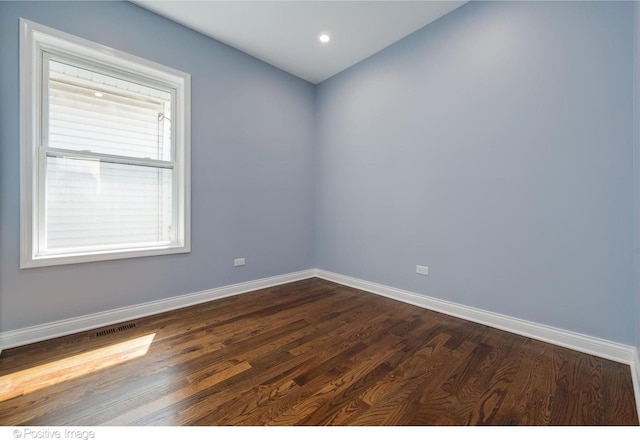 spare room with plenty of natural light and dark wood-type flooring