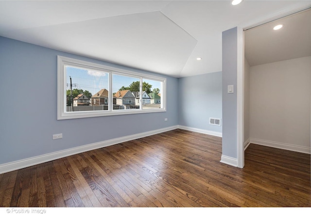 spare room featuring dark hardwood / wood-style floors and lofted ceiling