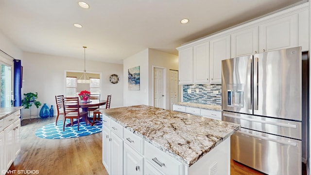 kitchen featuring white cabinetry, stainless steel fridge, tasteful backsplash, and a kitchen island