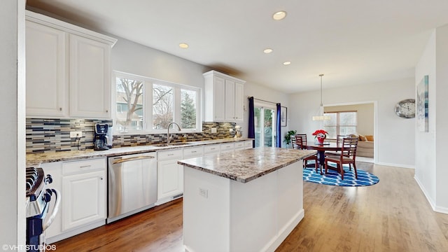 kitchen with a center island, white cabinets, sink, stainless steel dishwasher, and range