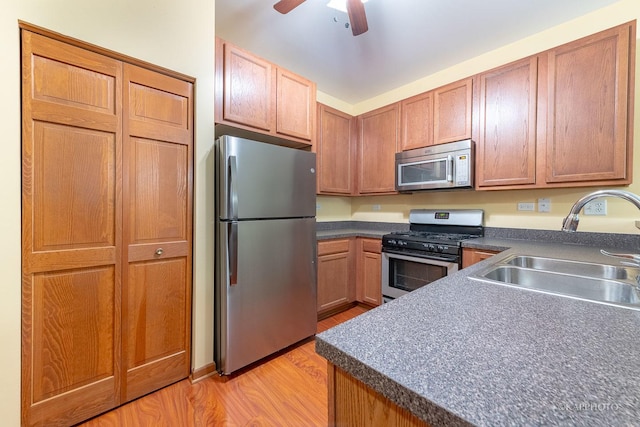 kitchen with ceiling fan, sink, stainless steel appliances, and light wood-type flooring