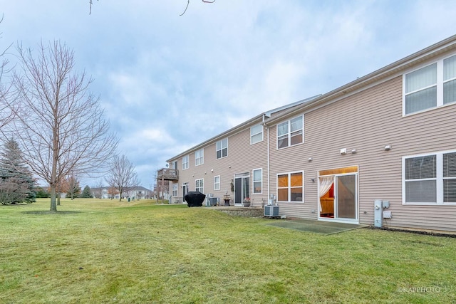 rear view of property with central AC and a yard